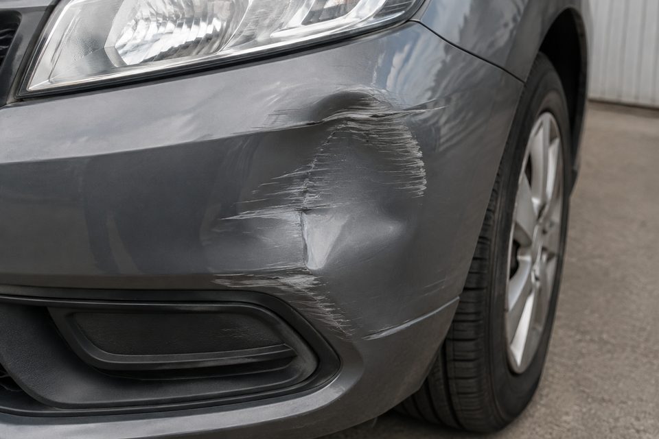 Beschädigter Stoßfänger eines grauen Fahrzeugs. KI-generiertes Symbolbild, kein Kundenfall.